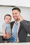 Businessman carrying baby boy while on call