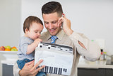 Businessman with documents carrying baby while on call