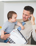 Businessman carrying baby and documents while on call