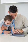 Businessman and baby boy using digital tablet