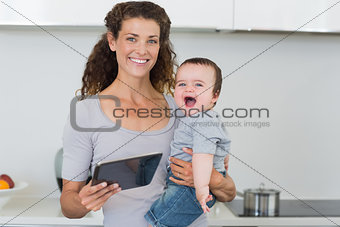 Happy mother with tablet carrying cheerful baby