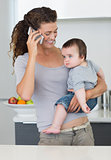 Mother using cellphone while carrying baby