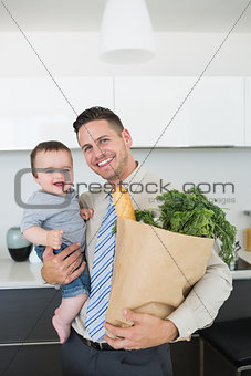 Father carrying baby boy and vegetables