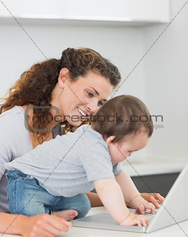 Mother looking at baby boy using laptop