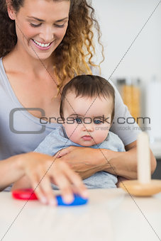 Baby looking at mother playing with toys