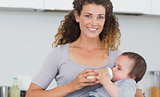 Attractive woman feeding milk to baby