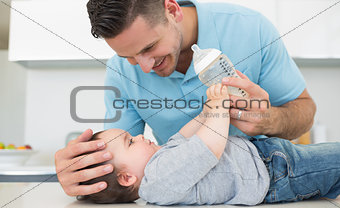 Caring father feeding milk to baby