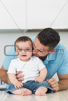 Loving father kissing baby sitting on counter