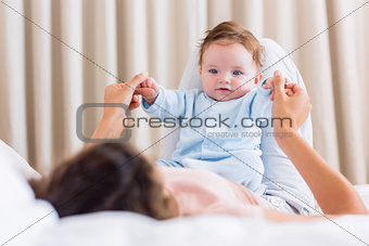 Baby playing with mother in bed
