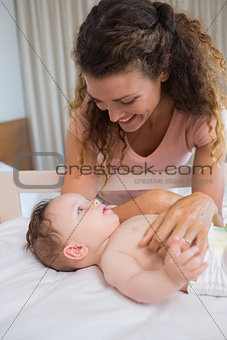 Mother looking at baby lying in crib