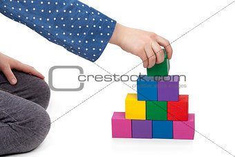 Child's hand building a brick tower isolated on white background