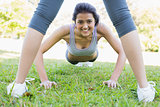 Smiling woman doing push ups in park