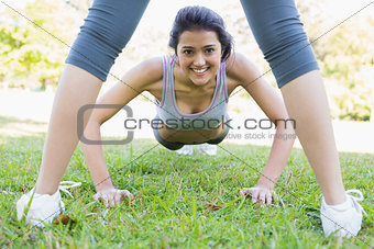 Smiling woman doing push ups in park