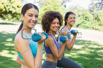 Friends lifting dumbbells in park