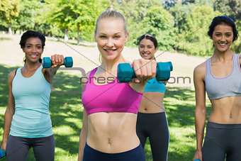 Women lifting weights in park