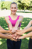Sporty woman stacking hands with friends