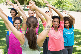 Women performing fitness dance with instructor at park
