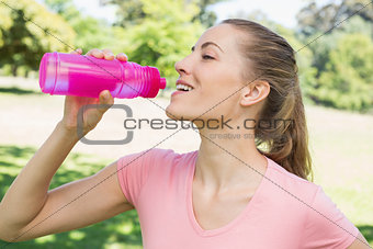 Sporty woman drinking water at park