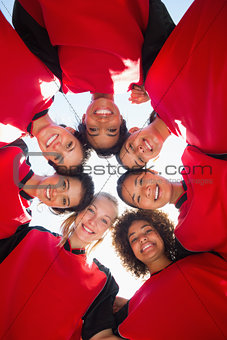 Female soccer team forming huddle against sky