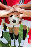Soccer team stacking hands on ball
