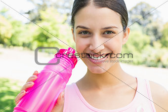 Happy sporty woman holding water bottle
