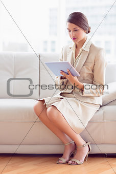 Pretty businesswoman sitting on sofa using tablet pc