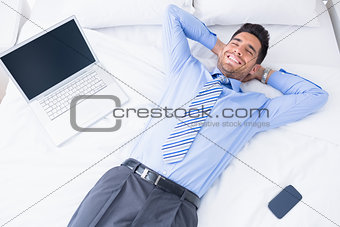 Happy businessman lying on his bed