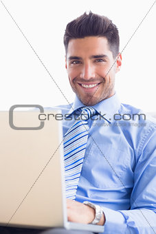 Happy businessman on couch using his laptop