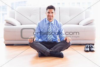 Handsome businessman sitting in lotus pose on the floor