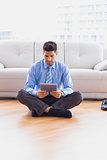 Businessman sitting on the floor using tablet