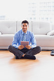 Businessman sitting on the floor using tablet smiling at camera
