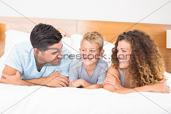 Happy young family lying on bed looking at each other