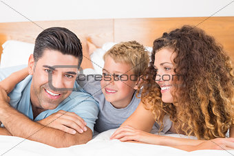 Smiling young family lying on bed together