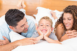 Cute young family lying on bed together smiling
