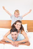 Happy young family smiling at camera on bed posing