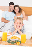 Smiling young family having breakfast in bed