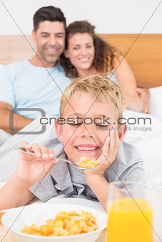 Cute young family having breakfast in bed