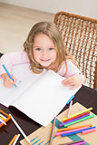 Smiling little girl colouring at the table