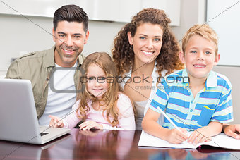 Happy parents colouring and using laptop with their young children