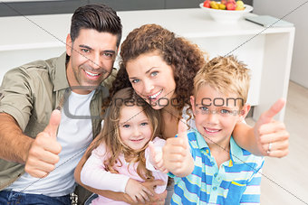 Happy parents giving thumbs up with their young children