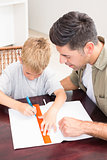 Father helping son with homework at table
