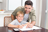 Cheerful father helping son with math homework at table