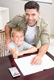 Happy father helping son with his math homework at table