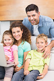 Happy family sitting on sofa using laptop