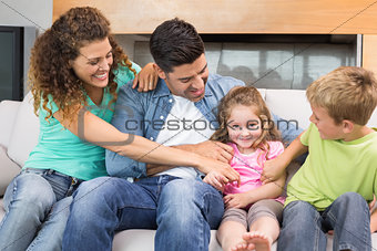 Cute family tickling little girl on the couch