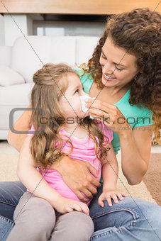 Mother helping her little daughter blow her nose