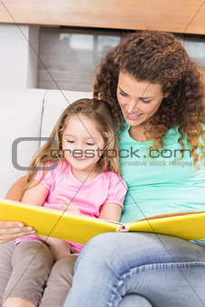 Pretty mother helping her little daughter read a storybook