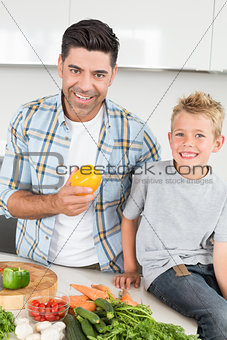 Smiling father holding a yellow pepper with his son