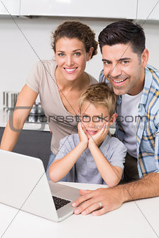 Smiling parents using laptop with their son