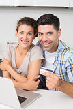 Attractive couple using laptop together to shop online